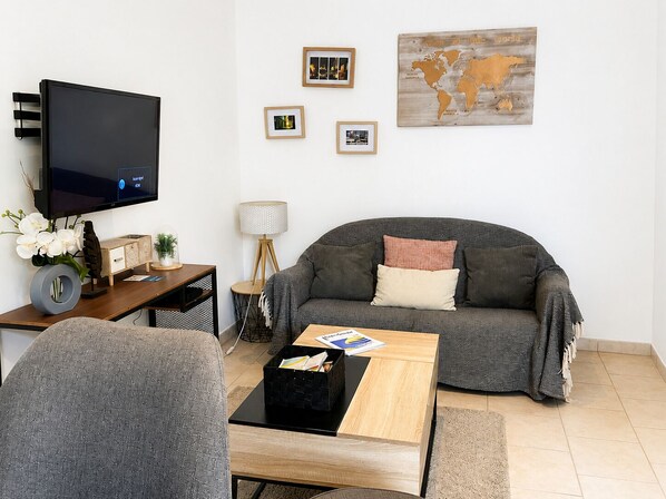 Olohuone, jossa on televisio, sohva, sohvapöytä ja seinällä kehyksiin asetettuja kuvia.