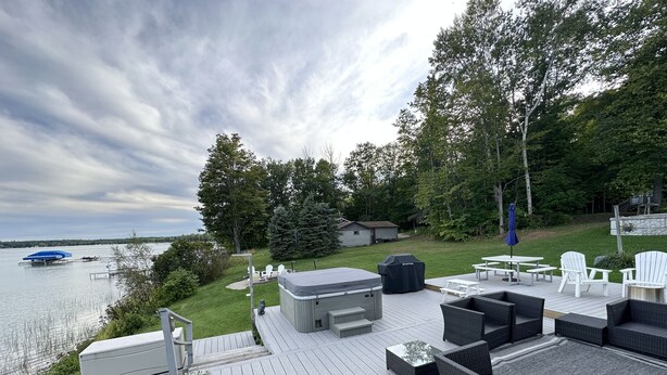 Um terraço com mobiliário externo, uma banheira de hidromassagem e vista para o lago.