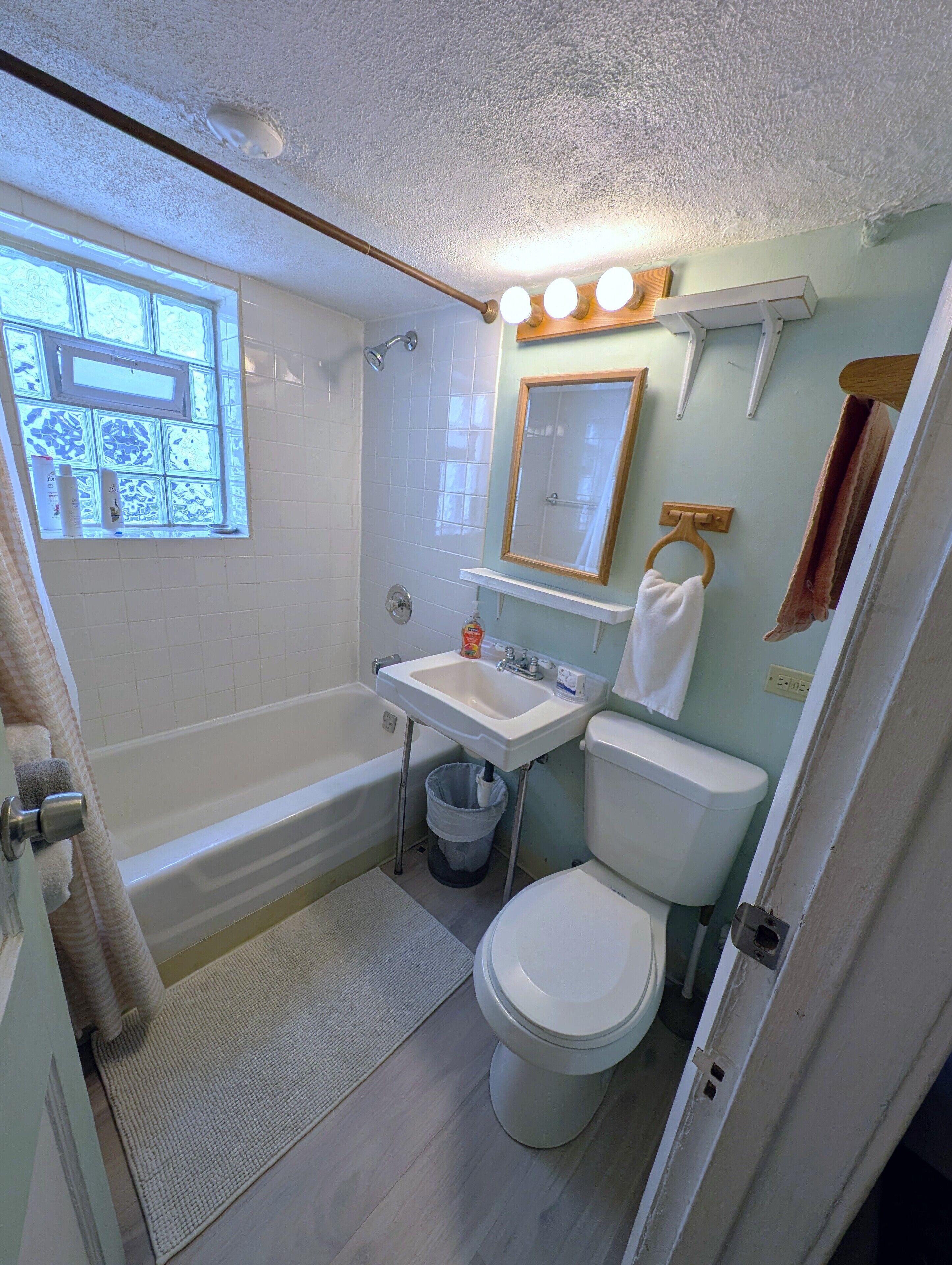 A bathroom with a bathtub, toilet, sink, and a window with patterned glass.