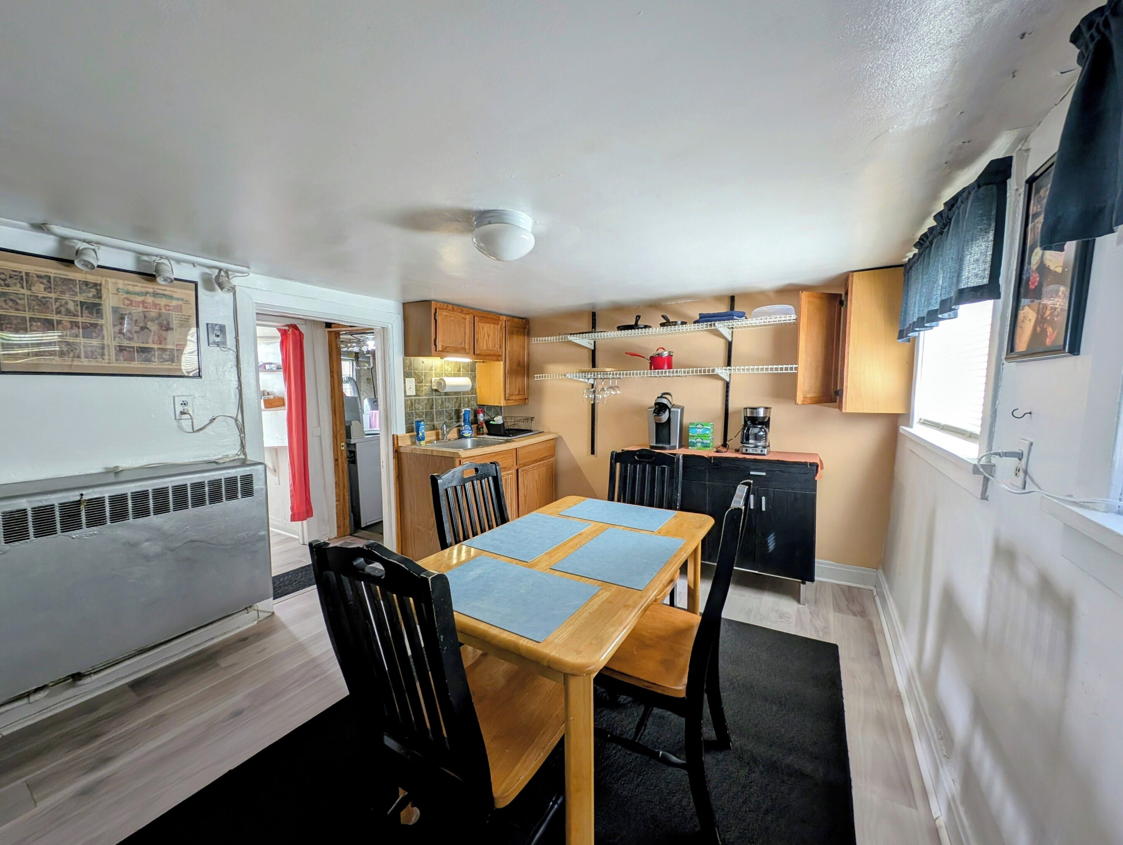A compact kitchen with a dining table, chairs, and a refrigerator.