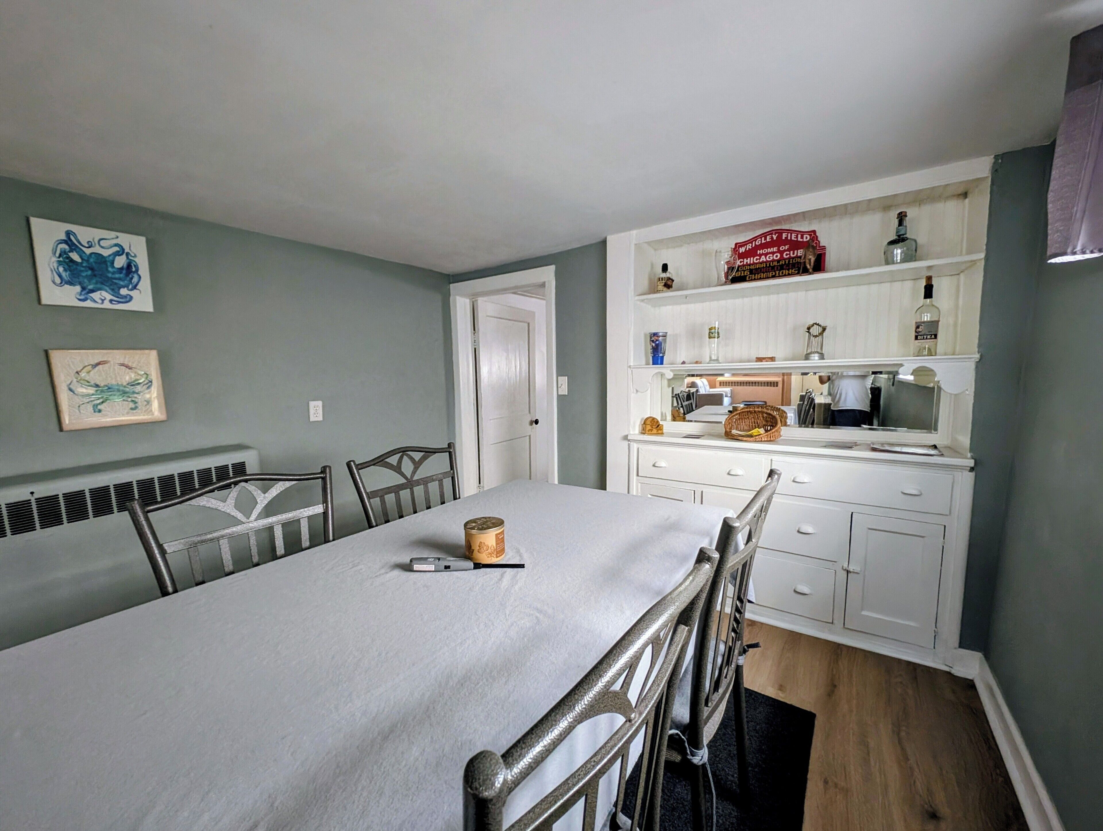 A dining area with a table, chairs, and a white cabinet with shelves.