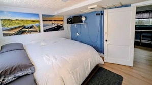 Ein Schlafzimmer mit Bett, Wandfernseher, Tür und Fenster.