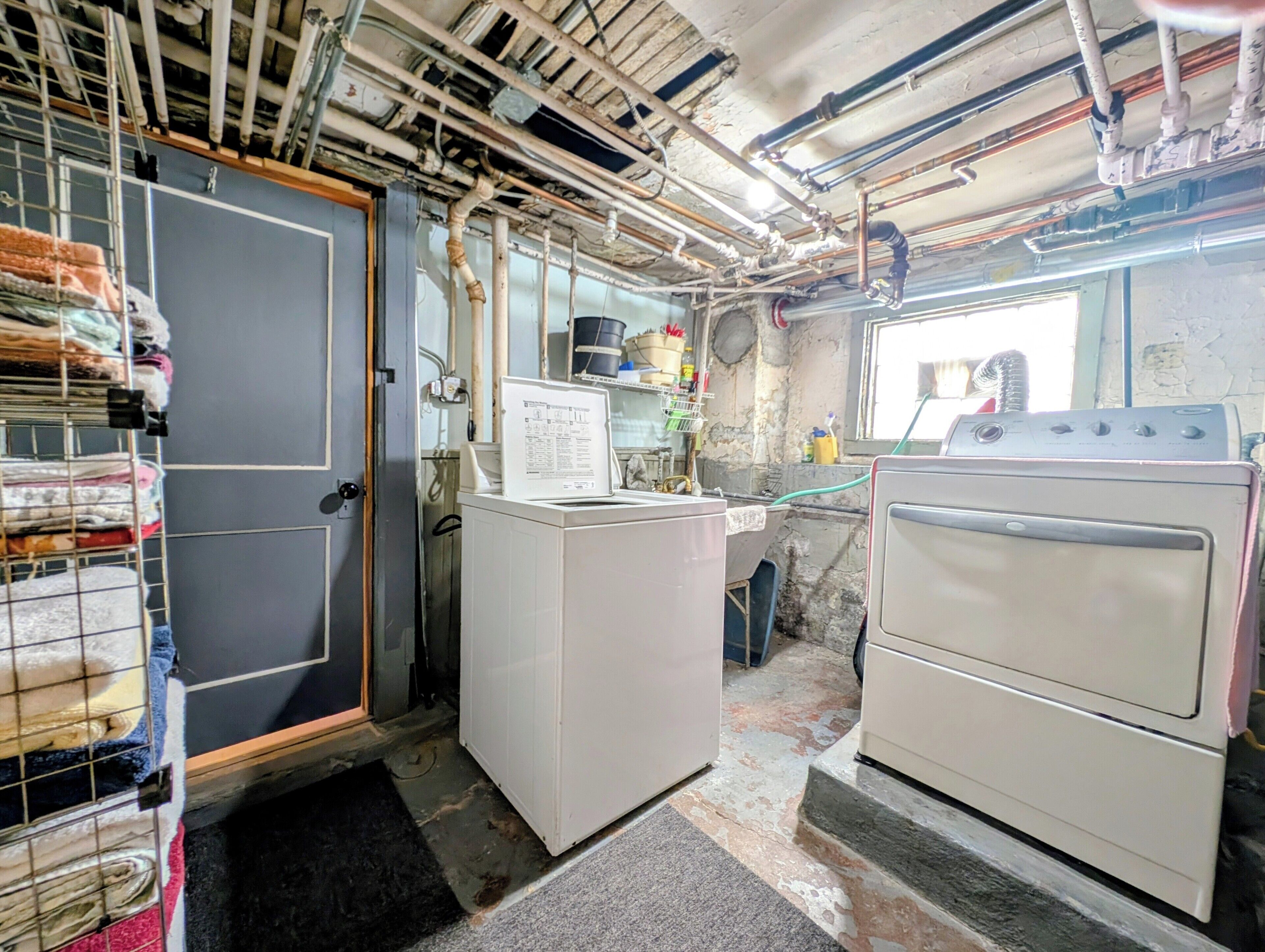 A laundry room with a washing machine, dryer, and stacked laundry on shelves.