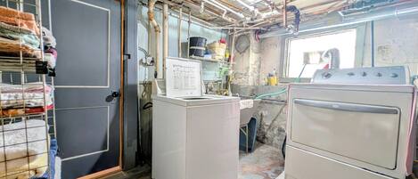 A laundry room with a washing machine, dryer, and stacked laundry on shelves.