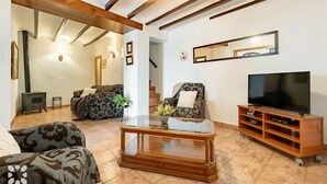 Een woonkamer met een bank, fauteuil, tv-meubel en een open haard.