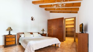 Een slaapkamer met een bed, een houten garderobe, nachtkastjes en een televisie.