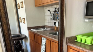 A kitchen with wooden cabinets, a stove, and a green tray. - STUDIO  Walking distance to beach. (Isla Verde)