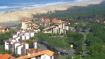 Un quartier résidentiel situé sur la côte, avec des immeubles à plusieurs étages, une plage en arrière-plan et une route qui traverse le domaine.