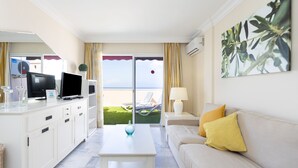 Une chambre d’hôtel avec un balcon, un canapé, une télévision, une table basse et un tableau.