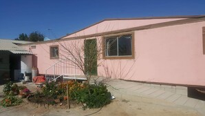 Un bâtiment rose avec un petit jardin devant.