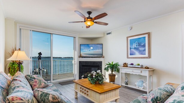 A living room with a sofa set, a coffee table, a fireplace, a television, and a balcony with a view. - Luxury condo with amazing bay front view (Ocean City)
