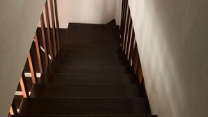 Eine schmale Treppe mit Holzhandläufen und einer weißen Wand.