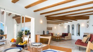 Un vaste espace de vie agrémenté de poutres en bois, une table à manger pour deux personnes et un coin salon confortable avec un canapé et des fauteuils.