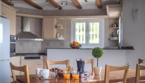 A kitchen with wooden cabinets, a coffee maker, a fruit bowl, and a potted plant on the table.