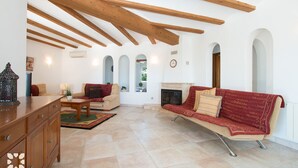 Un salon spacieux avec un plafond en bois, une cheminée et un canapé rouge.