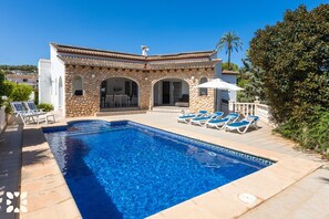 A poolside area with a stone building, a clear blue pool, and lounge chairs. - Villa SOLEADA by Abahana Villas (Calpe)