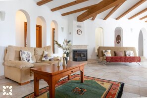 A living room with a sofa, a coffee table, a fireplace, and a patterned rug.