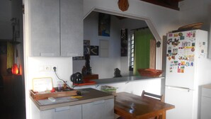 Eine kleine Küche mit Holztisch und -stühlen, einem weißen Kühlschrank und einer Arbeitsfläche.