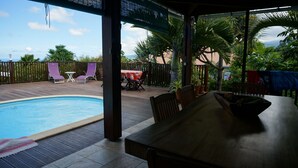 Ein überdachter Außenbereich mit Pool, Holzterrasse und Sitzgelegenheiten.