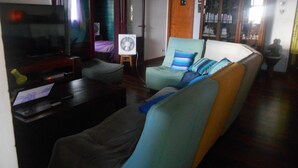 Ein Wohnzimmer mit Fernseher, Ventilator, Sofa und Schrank.