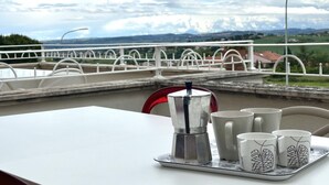 A table with a coffee maker and cups, a railing, and a view of a bridge and landscape. - S023 - Sirolo, magnificent design three-room apartment with terrace (Sirolo)