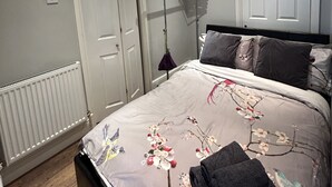Une chambre à coucher avec un lit, un radiateur, une armoire et une porte.