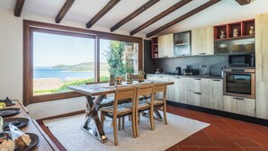 A kitchen with wooden beams, a large window, and a view of the sea. - Villa Caterina, amazing front sea 2 Br villa with private beach (Punta Molara)
