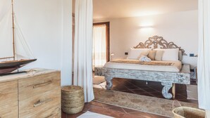 A bedroom with a bed, wooden dresser, and a sailboat model. - Villa Caterina, amazing front sea 2 Br villa with private beach (Punta Molara)