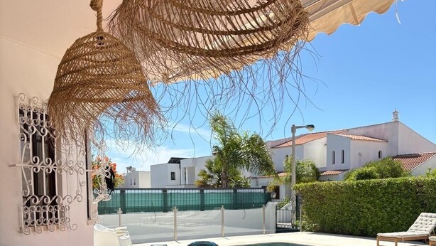 Zona de menjador amb vista a la piscina, sostre de vimbles i taula preparada per a quatre.