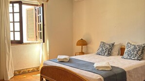 Un dormitori amb un llit, una finestra amb cortines, una làmpada de nit i un aire condicionat fixat a la paret.