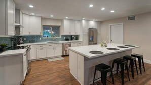 Une cuisine moderne avec des meubles blancs, un îlot central doté de tabourets et une fenêtre offrant une belle vue.