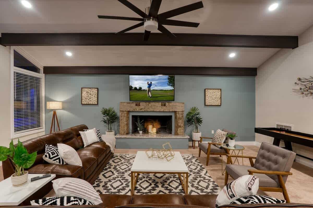 A modern living room with a fireplace, leather sofa, and a television mounted above it.