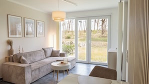 Una sala de estar moderna con un sofá modular, una mesa de centro redonda y vistas al exterior a través de grandes puertas correderas de vidrio.