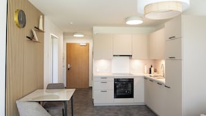 Una cocina moderna con armarios blancos, horno empotrado y comedor con mesa y sillas.