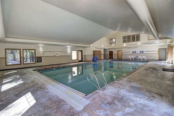 Una piscina interior con agua cristalina, suelo de baldosas y techo alto.