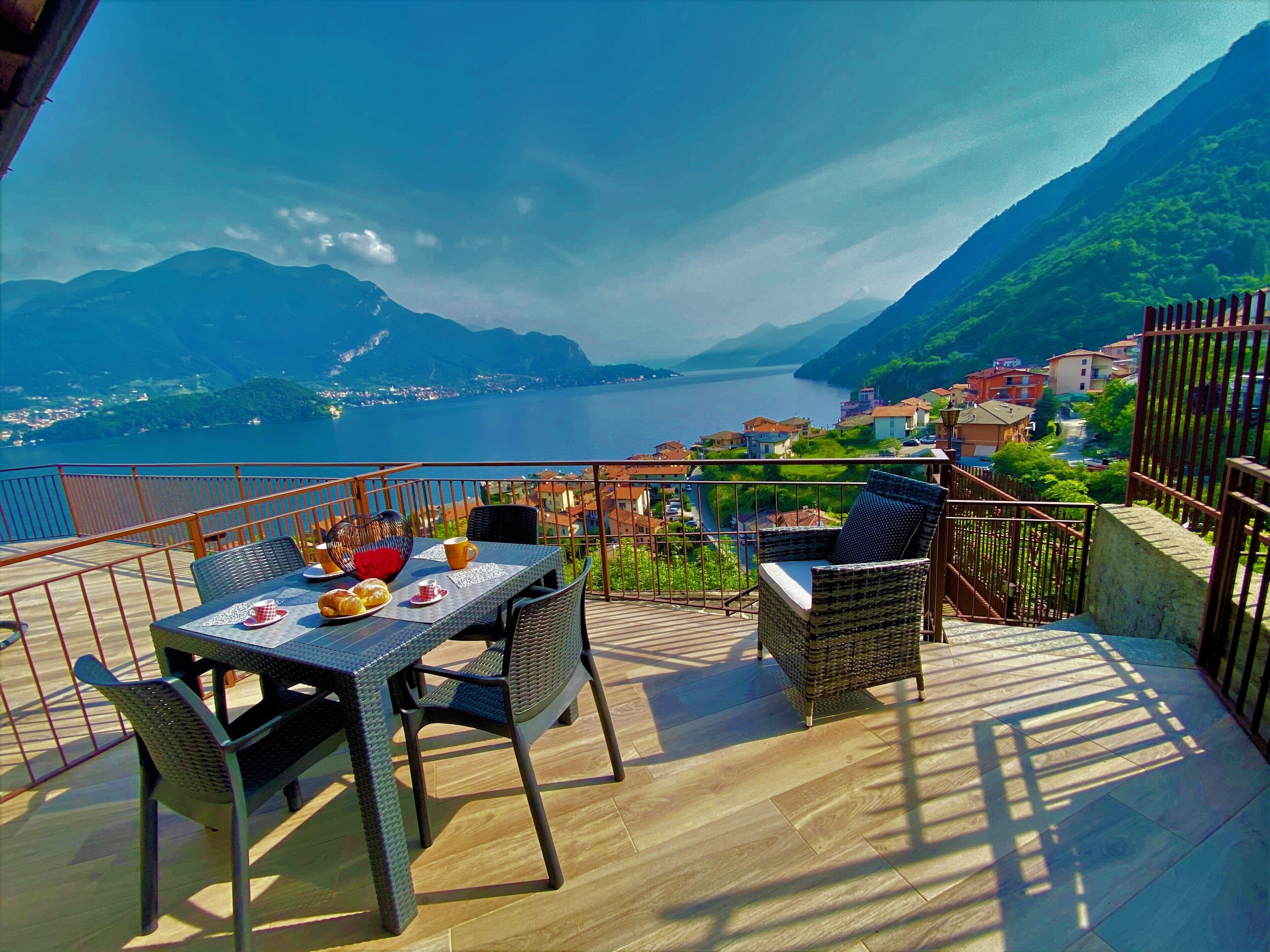 Eine Terrasse mit einem Tisch für zwei Personen mit Blick auf einen See und Berge.