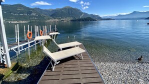 A wooden dock with lifebuoys, clear water, and mountains in the background. - RUBINO NEW!  NEAR BELLAGIO! BALCONY GARDEN, &  STUNNING VIEW! (lezzeno)