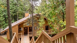 A wooden cabin with a balcony, surrounded by trees. - Escape to Ptarmigan Village 79 (Whitefish)