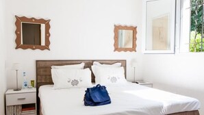 A hotel room with a large bed, two nightstands, and two wall-mounted mirrors. - House in a residence for 8 person (s) - Lumio (St Ambroggio Lumio)