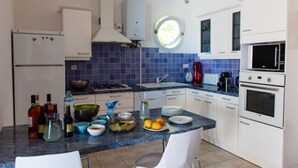 A modern kitchen with white cabinets, a blue tiled backsplash, a gas stove, a sink, and a microwave. - House in a residence for 8 person (s) - Lumio (St Ambroggio Lumio)
