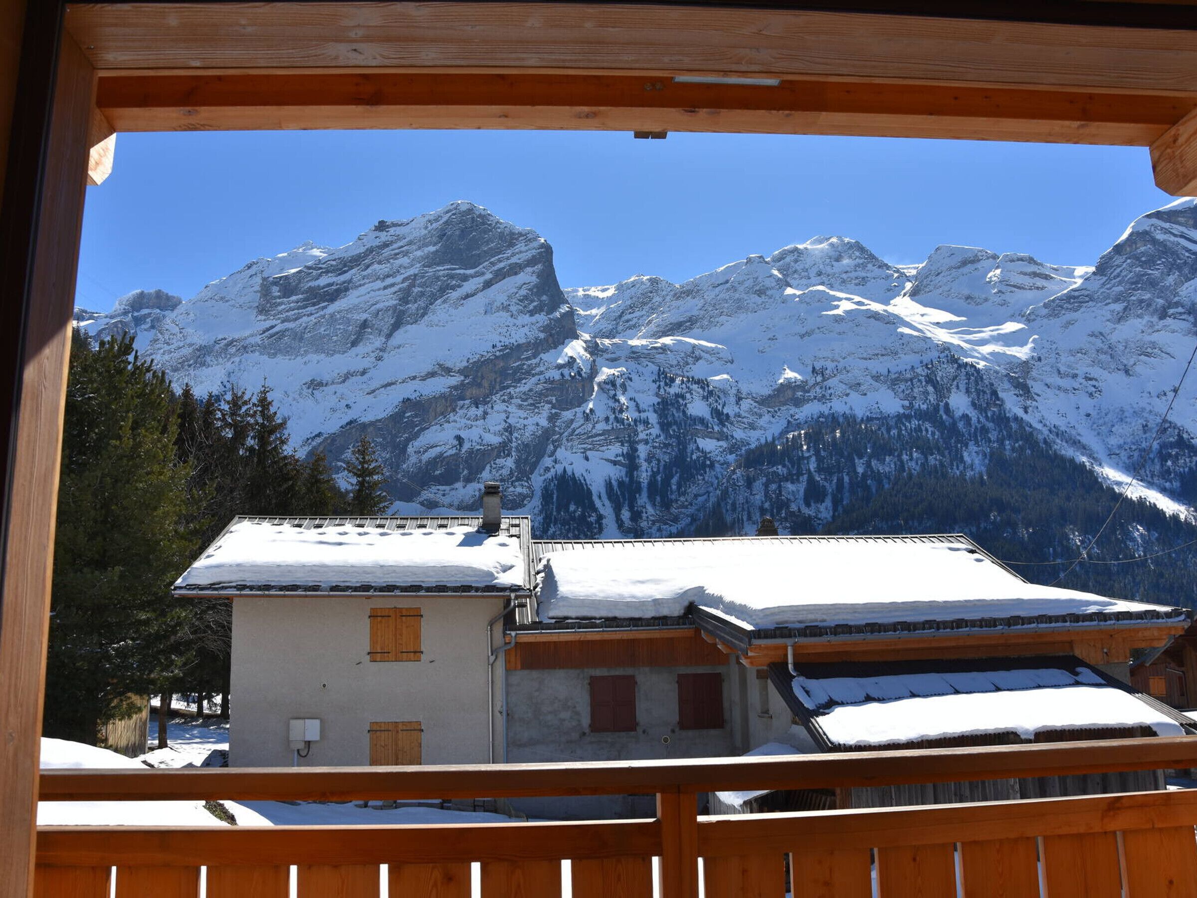 Ein Chalet mit verschneitem Dach und Blick auf schneebedeckte Berge.