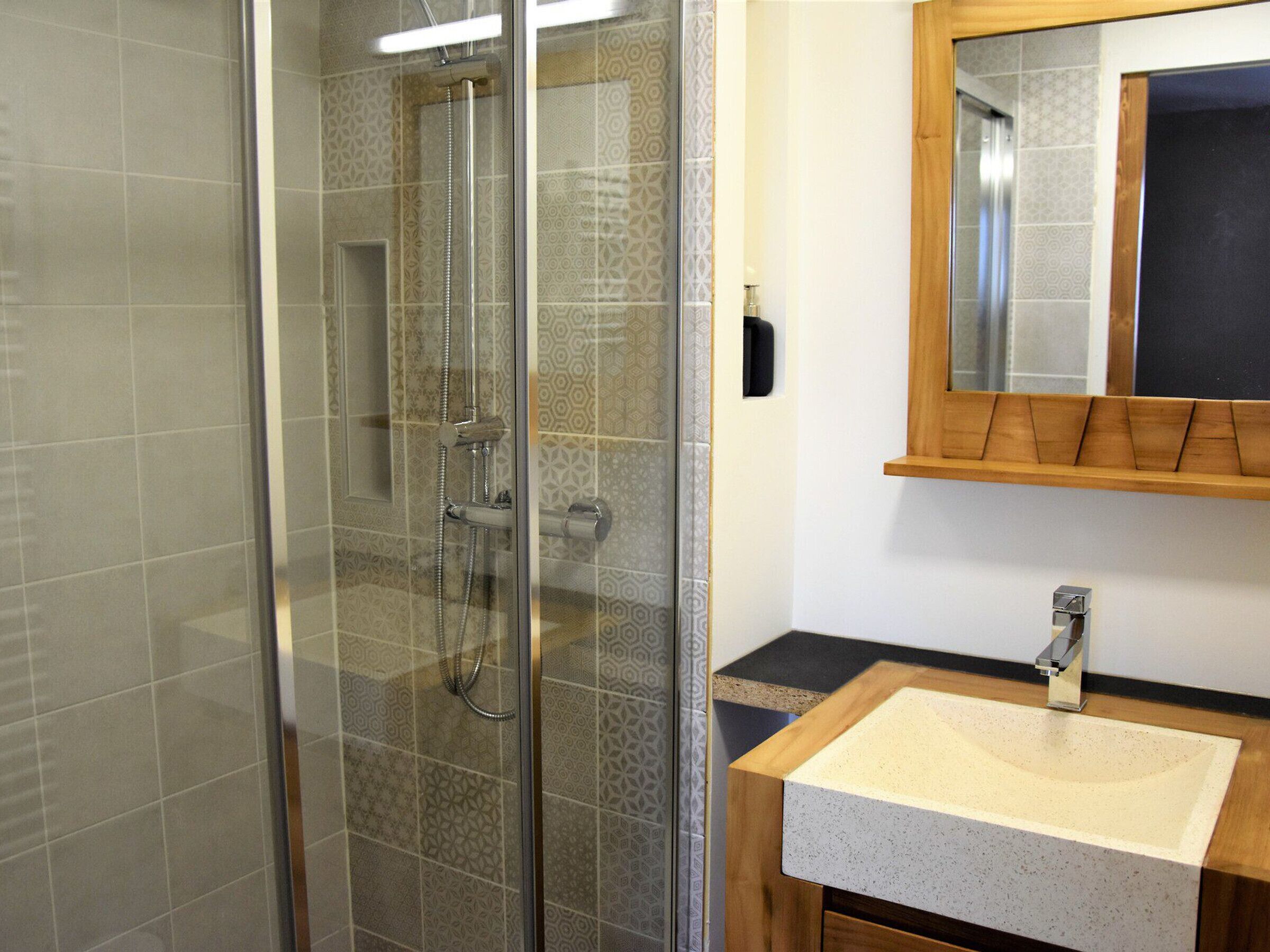 A bathroom with a glass-enclosed shower, a wooden vanity with a sink, and a mirror above the vanity.