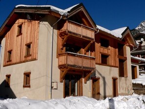 A wooden chalet with a balcony, a snow-covered roof, and a mountain backdrop. - Beautiful new 1-bedroom, south balcony, ideal for 4 (Pralognan-la-Vanoise)