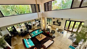 A spacious living area with a high ceiling, a large sofa set, and a dining table. - 120 +5 STAR reviews below 3 Min to Beach English speaking Chef  Butler Meal Plan (La Romana)