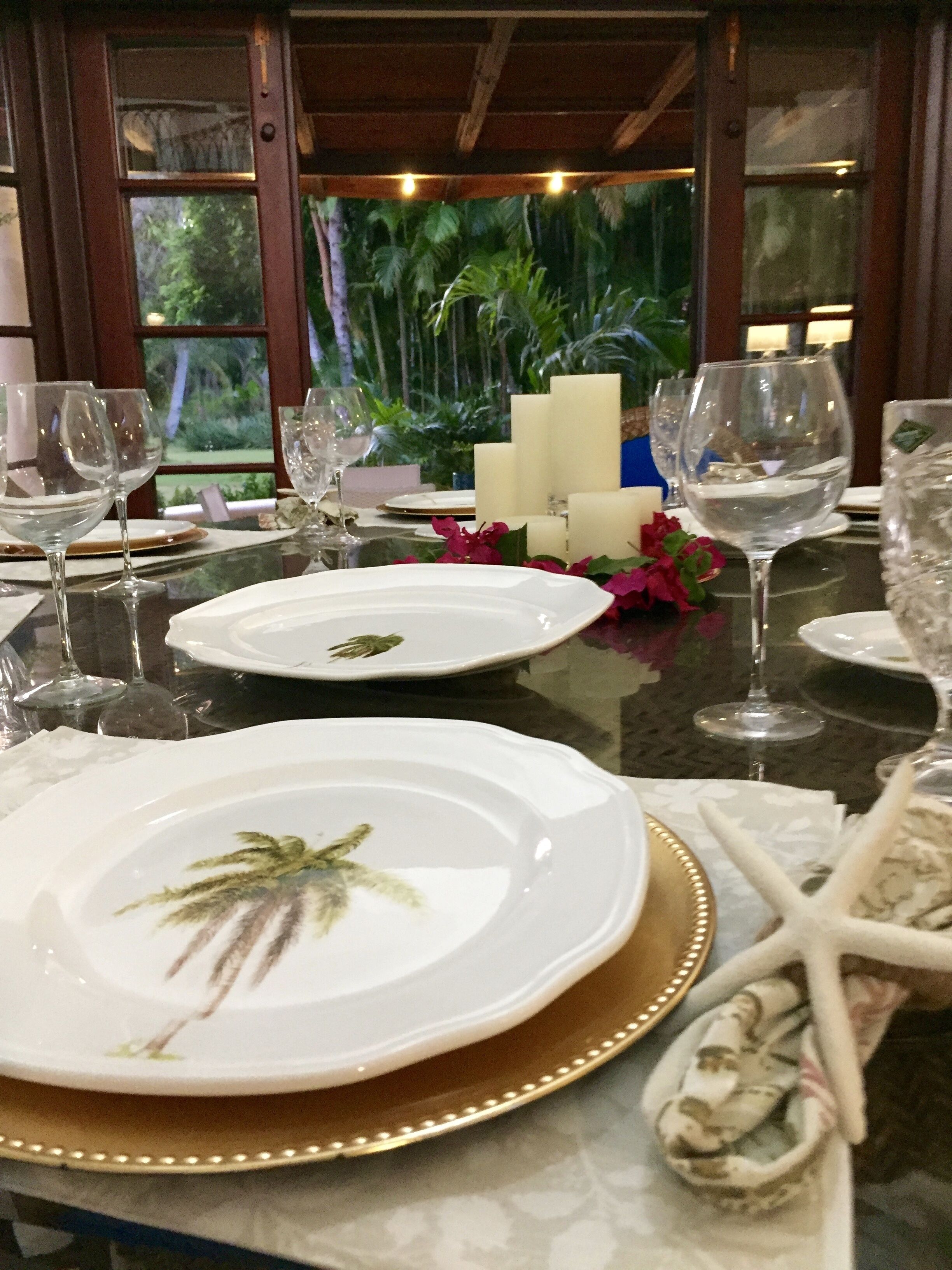 Una mesa lista para comer, con platos blancos, vasos y velas.