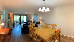 Een ruime woonkamer met een houten eettafel en stoelen, een bank en een balkon met uitzicht.