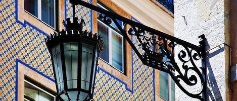 Een traditionele straatlamp met een decoratief ontwerp, bevestigd aan een gebouw met een geornamenteerd gevel.