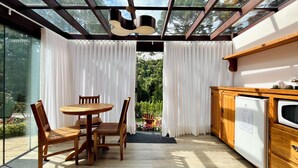Una cocina con un armario de madera, un microondas integrado y una ventana con vistas a un jardín.