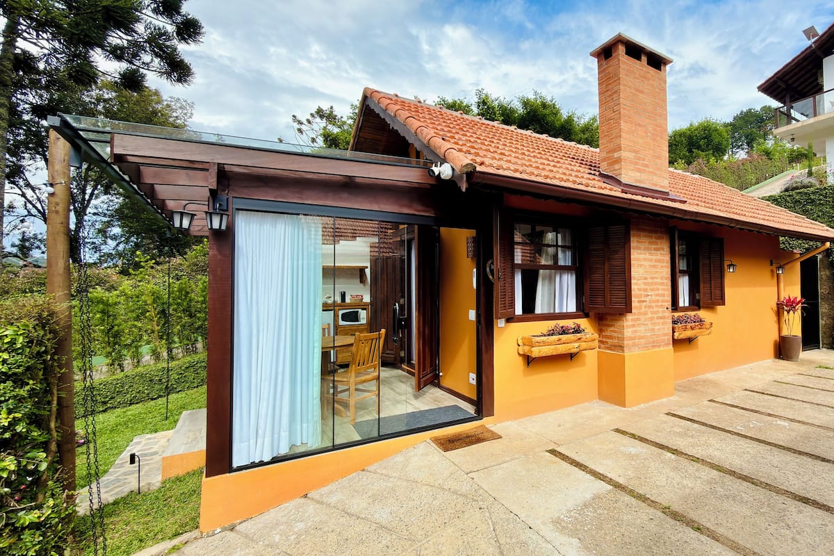 A modern house with a glass entrance, a brick chimney, and a small garden area.