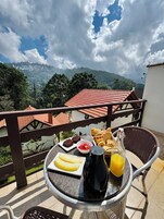 Varanda com mesa posta para o café da manhã, incluindo pão, frutas e uma bebida.